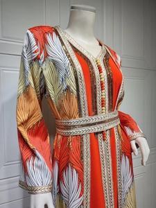 Detail of orange Moroccan kaftan dress with gold embroidery and leaf pattern prints