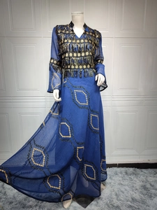 Close-up of deep blue evening dress with intricate gold bead embroidery and black tassels