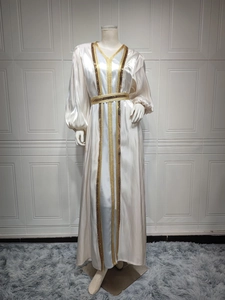 Detail of golden sequined embroidery and shiny satin fabric on a white kaftan set