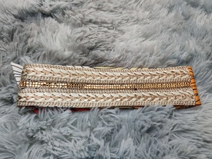 Detail of premium braided ribbon with gold sequins and embroidery on a long dress
