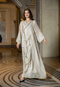 Elegant ivory kaftan dress with gold sequin embroidery in a luxurious hallway setting