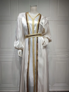 Close-up of white satin kaftan featuring gold embroidery and brown sequin trim details