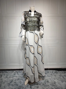 Detailed close-up of white sequin dress featuring ethnic gold tassels and black embroidery