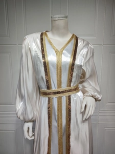 Detail of elegant cream satin kaftan dress featuring gold and brown beadwork embroidery