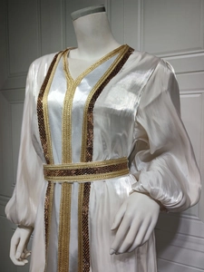 Detail of satin dress with golden woven trim, sequins and elegant lantern sleeves