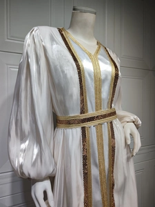 Detail of white satin dress featuring intricate gold embroidery and elegant lantern sleeves
