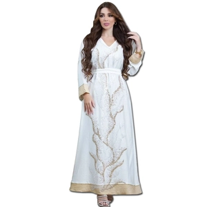 Détail d'une robe abaya blanche à manches longues avec broderie de paillettes dorées