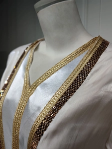 Detailed V-neckline of luxury white satin dress with golden embroidery and rhinestones