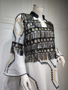 Detail of white kaftan dress with gold sequin embroidery and long tassel fringes