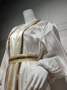 Close-up of white satin dress with intricate gold embroidery and sequin details