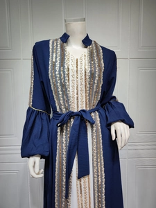 Close-up of dark blue dress featuring vertical gold sequin embroidery and flared sleeves