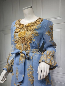Close-up of gold sequin embroidery on light blue ethnic party dress with tied waist belt
