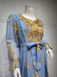 Detail of light blue ethnic dress with golden floral embroidery and sequins on chest