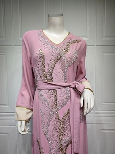 Détail de la broderie à paillettes sur robe rose à col en V avec bordure dorée
