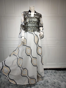 Detail of white evening dress featuring gold sequins, fringe tassels and geometric embroidery