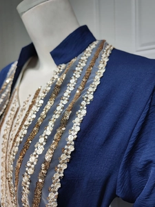 Detailed close-up of gold and white sequin embroidery on a navy blue kaftan robe