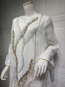 Detailed view of elegant white summer dress featuring gold and silver sequin wave patterns