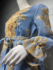 Detailed close-up of gold embroidery and sequins on light blue long-sleeved evening dress