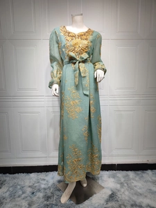 Close-up of golden floral embroidery and sequins on a dark green ethnic evening gown