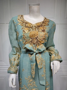 Detailed close-up of intricate gold embroidery and sequins on a teal maxi dress