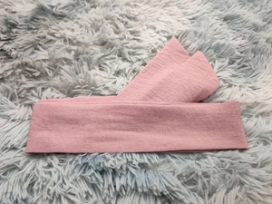 Détail du bandeau large en tissu rose poudré montrant la texture douce du coton sur fourrure
