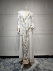 Détail d'un caftan blanc à col en V avec des broderies de paillettes dorées et argentées
