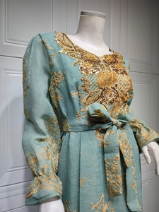 Close-up of golden floral embroidery and sequins on light blue ethnic long dress