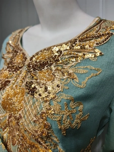 Close-up of intricate gold and bronze sequin embroidery on green ethnic party dress