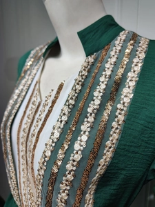 Detailed embroidery with gold sequins and white floral lace on dark green ethnic dress
