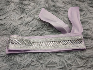 Detail of purple satin belt featuring elegant silver sequins and rhinestone embellishments