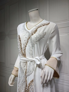 Vue détaillée de la robe blanche à manches longues avec broderie de paillettes or et argent