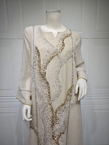Close-up of gold and silver sequin embroidery on beige linen kaftan dress.