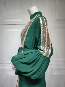 Close-up of golden sequin embroidery details on forest green bishop sleeve dress