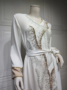 Détail de la broderie de paillettes dorées et argentées sur la manche d'un caftan blanc