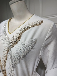 Gros plan d'une blouse en crêpe blanc avec col en V doré et broderies de paillettes