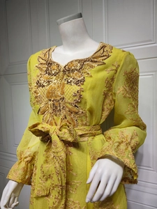 Close-up of golden embroidery and sequins on bright yellow chiffon evening dress