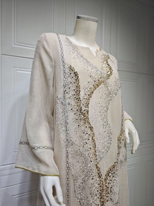 Detailed shot of a beige linen dress featuring gold and silver sequin embroidery