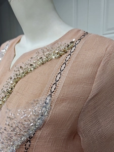 Close-up of elegant sequins and geometric embroidery on a peach linen summer dress