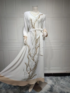 Détail de broderie sur une robe Abaya blanche à paillettes avec manches longues et liseré
