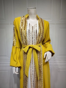 Macro detail of sequin embroidery and silver stripes on the yellow abaya sleeve