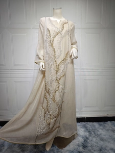 Close-up of elegant beige kaftan with intricate gold and silver sequin embroidery