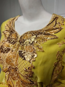 Close-up of golden embroidery and sequins on the collar of a yellow ethnic dress