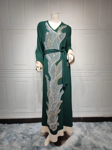 Détail d'une robe Abaya vert foncé ornée de broderies en dentelle à paillettes or et argent