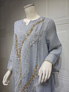 Close-up detail of shimmering gold and silver sequins on a light blue summer linen dress
