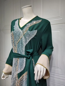 Détail de la broderie de dentelle blanche et sequins dorés sur une robe kaftan verte