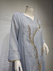 Detailed view of grey-blue kaftan dress with gold and silver sequin embroidery