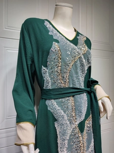 Détail de la broderie en dentelle à paillettes sur une robe ethnique vert foncé