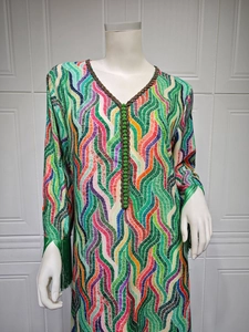 Close-up of the V-neck detail and fringe cuffs on a colorful bohemian print dress