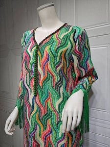 Detail of V-neckline with green beaded buttons and long tassels on print dress