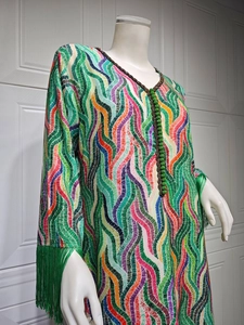 Detailed view of colorful wavy print and green tassels on long sleeve V-neck dress